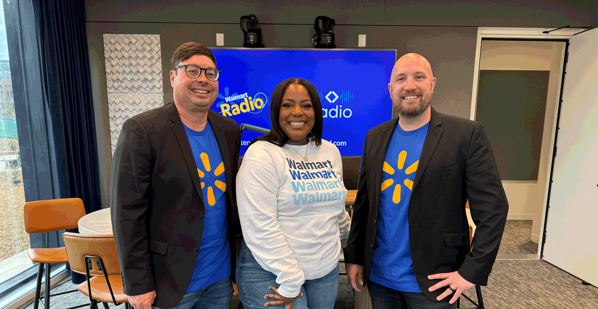 On-air personalities Chris, Kirby and Bo pose in front of a Walmart & Sam's Club Radio banner